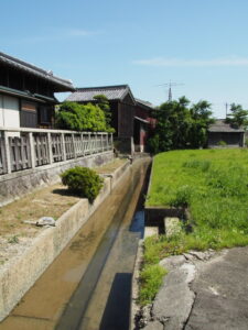 民家の脇を流れる用水路（松阪市和屋町）